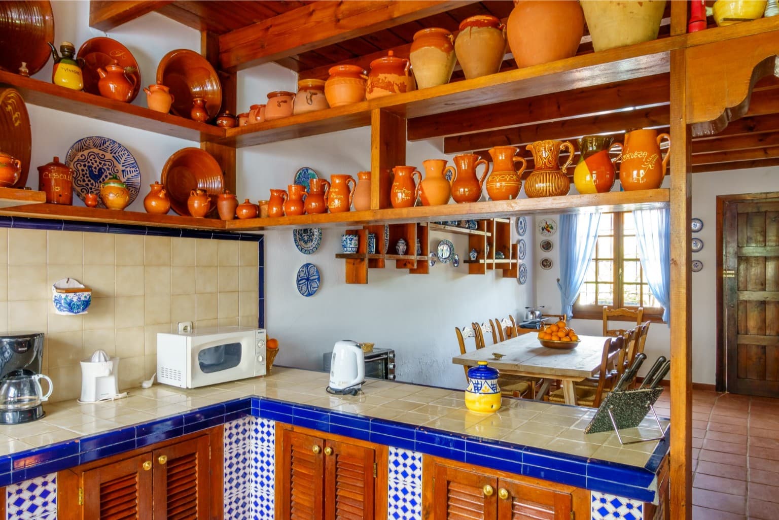 Kitchen shelves filled with traditional clay pottery and pitchers.