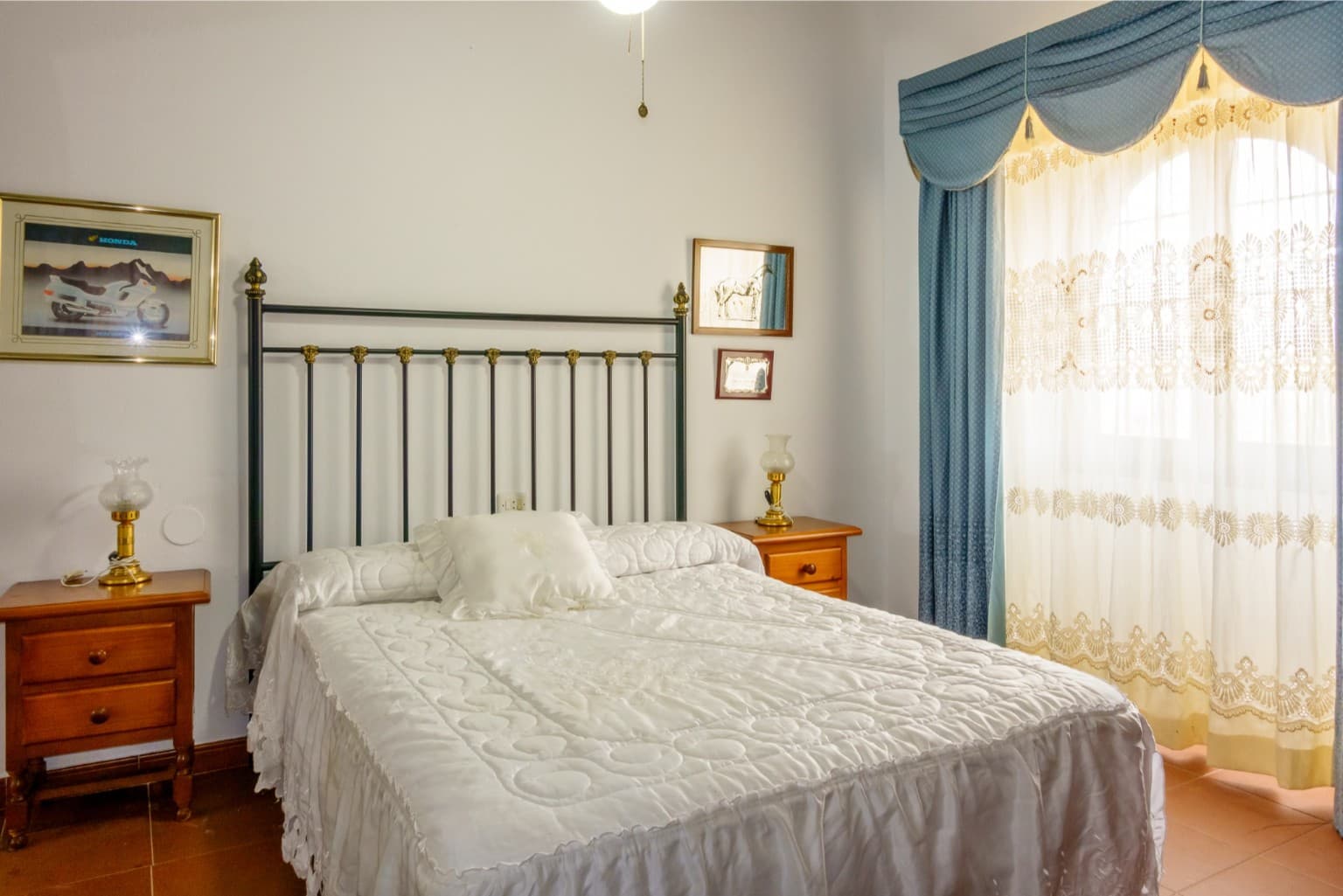 Bright bedroom featuring a metal bed frame and blue curtains.