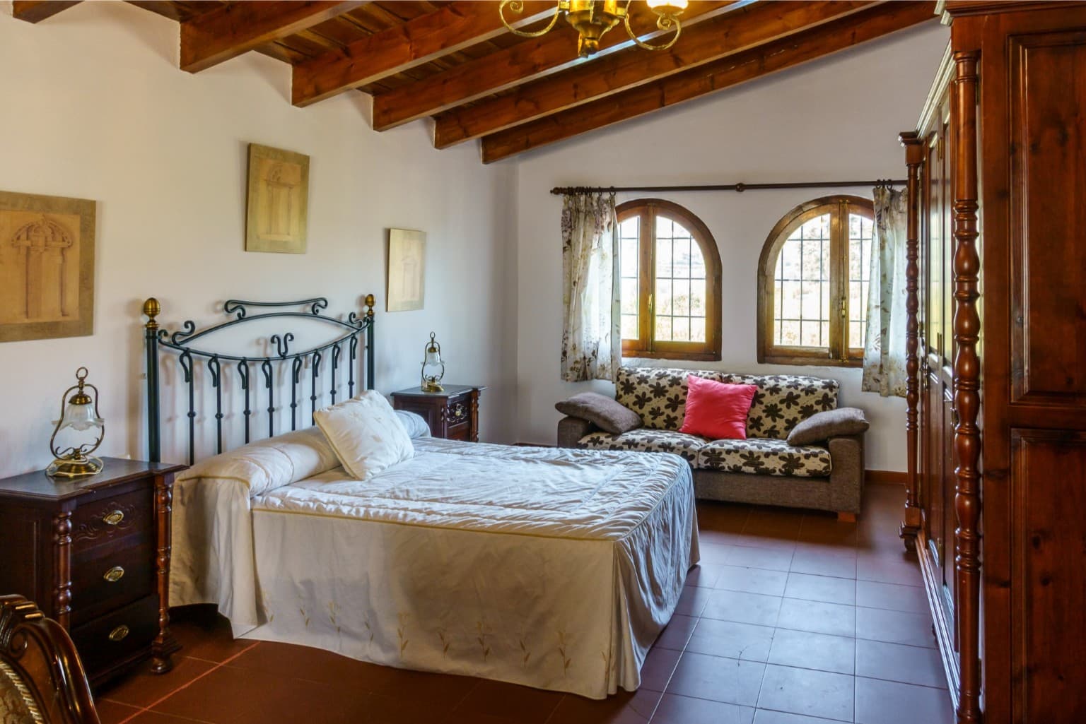 Spacious master bedroom with high wooden ceilings and arched windows.
