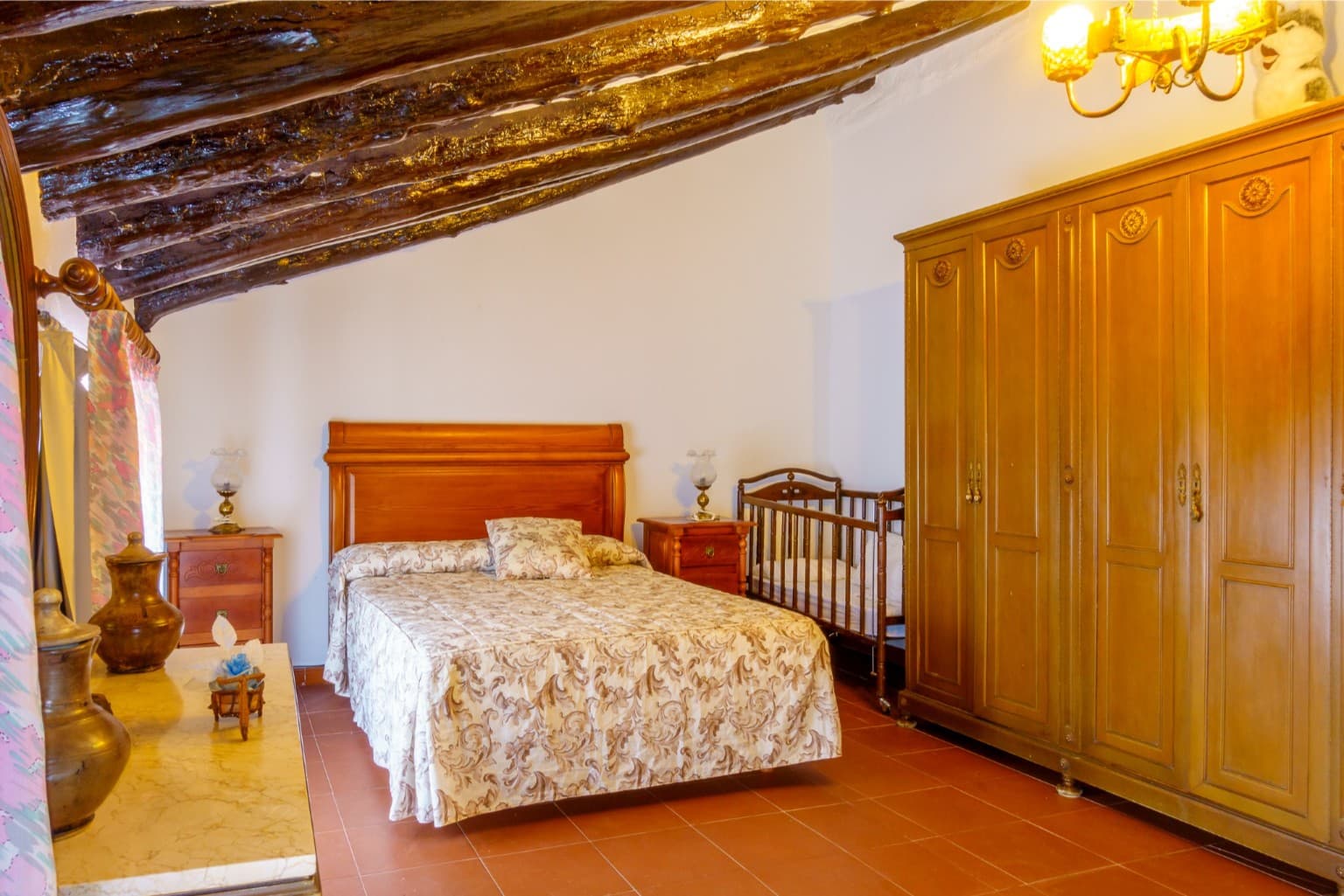 Charming attic bedroom with exposed wooden beams and crib.